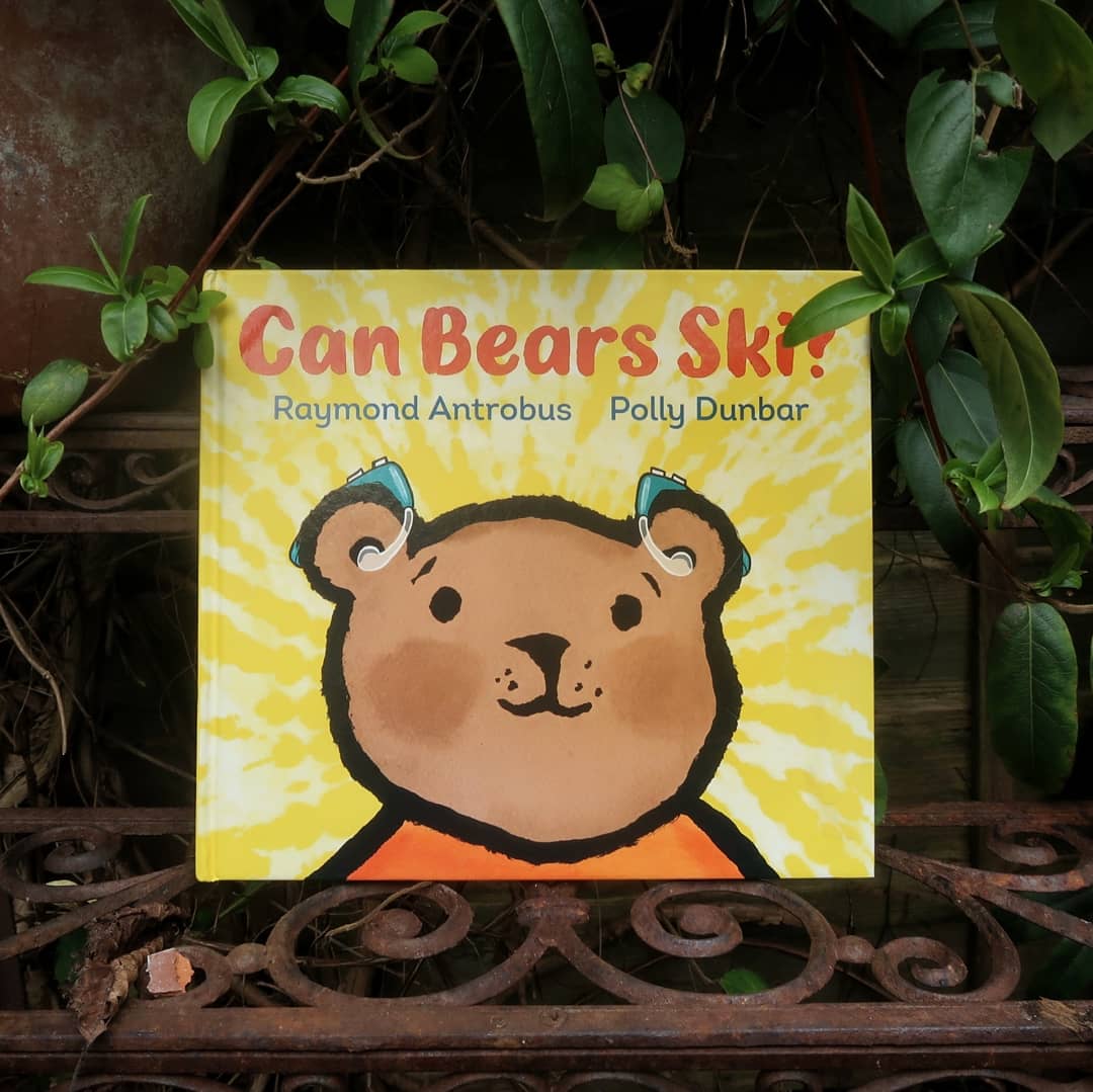 A book portrait of Can Bears Ski? It's a yellow picture book with a brown bear's face in close-up on the front. The bear wears hearing aids.