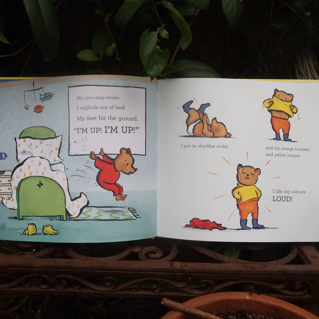 Inside pages of Can Bears Ski? - a double page spread - the small joyful anthropomorphised bear is bouncing out of bed. "I'm up!" "I like my colours LOUD!"
