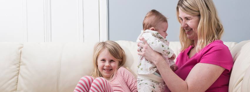 A photo of Lisa Wells - a white mother with blonde hair - with her daughters, the youngest is newborn.
