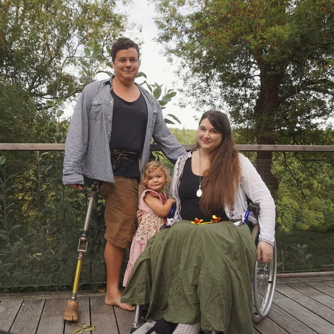 A photo showing Lucy is a wheelchair user in a manual chair, and James is an amputee - with a prosthetic leg over his clothes.