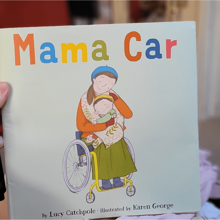 Mama Car - blads of the US edition. (An early stapled and bound rough version.) Book cover: A white mother with brown hair in a ponytail sits in her yellow wheelchair, cradling her child of 3yo or so on her lap. She’s looking slightly down at the girl, lovingly, while the girl’s snuggled into her, smiling. The mother wears a long dark green skirt, dark orange cardigan and dark red gloves, and a blue beret. The background is pale green. ‘Lucy Catchpole’ and ‘Karen George’ are at the bottom, title ‘Mama Car’ is at the top in large print, in the same colour palette as the mother’s clothes